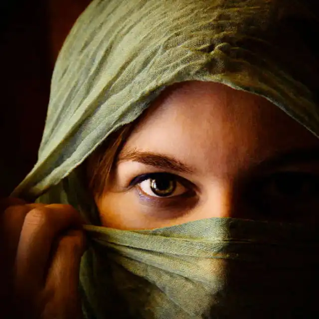 Woman with green veil over head and nose and just showing eyes